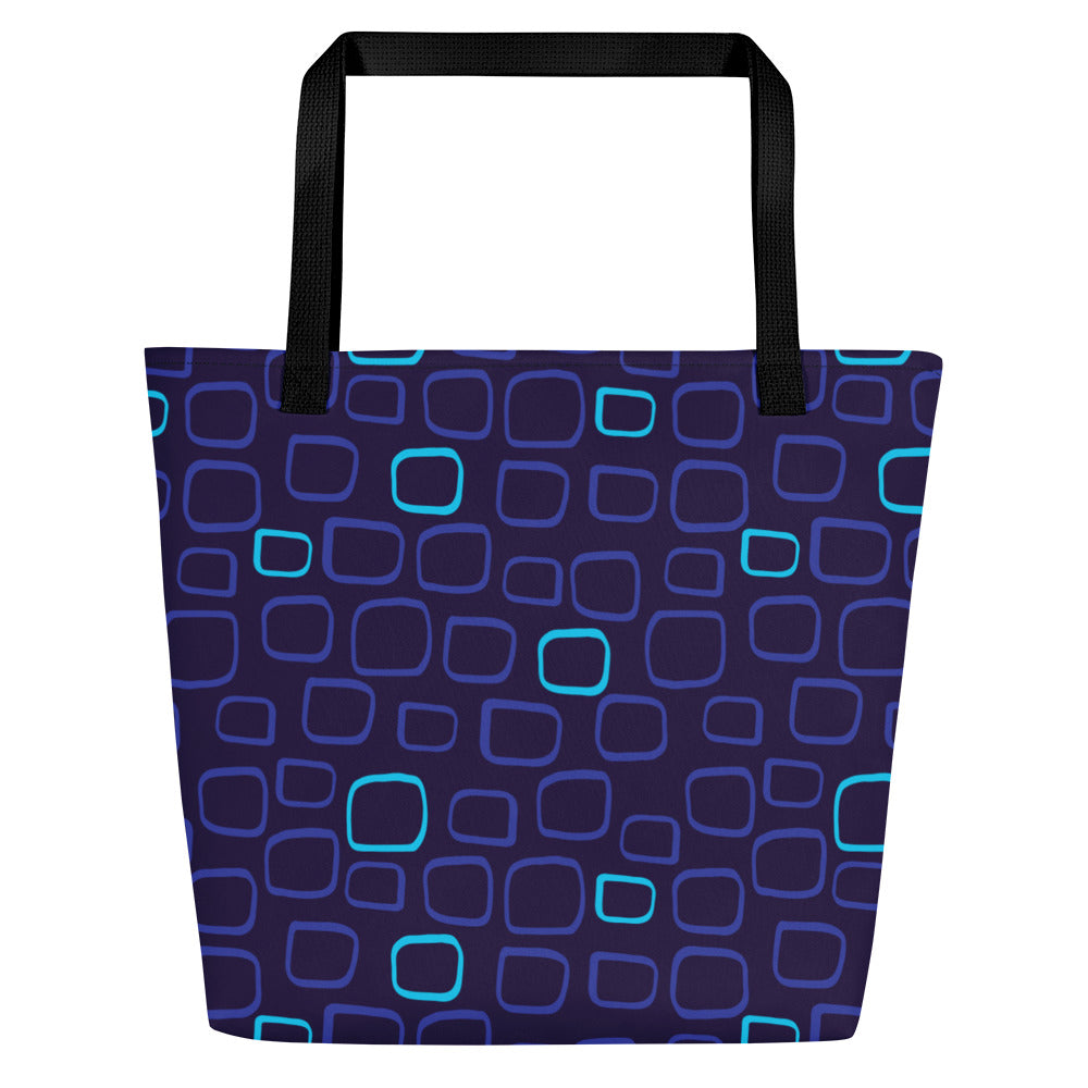 Tote bag with a dark blue background features a pattern of irregularly shaped squares in light blue and purple tones. Black handles provide contrast.