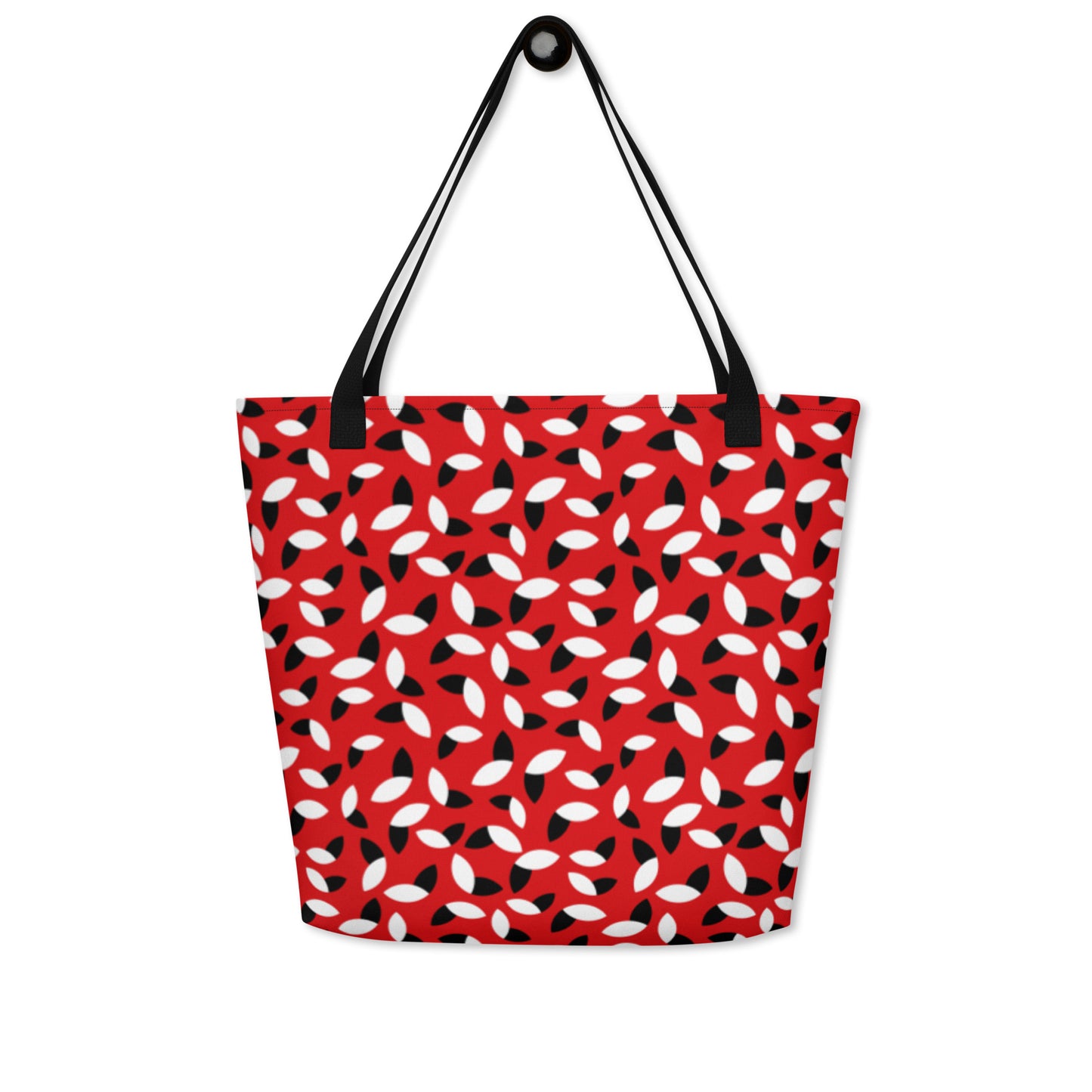 Red tote bag with a bold pattern of alternating black and white petal shapes. Features sturdy black handles, creating a modern and vibrant look.