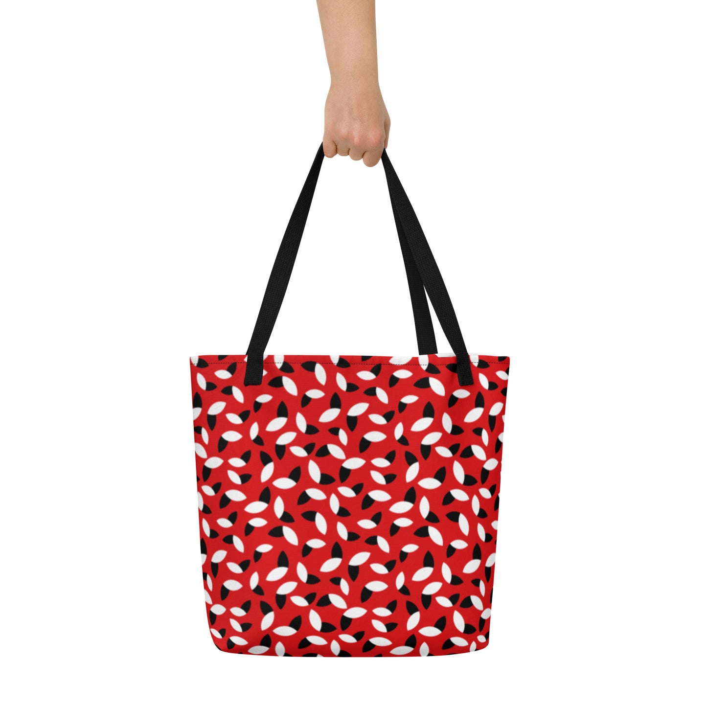 Red tote bag with a bold pattern of alternating black and white petal shapes. Features sturdy black handles, creating a modern and vibrant look.