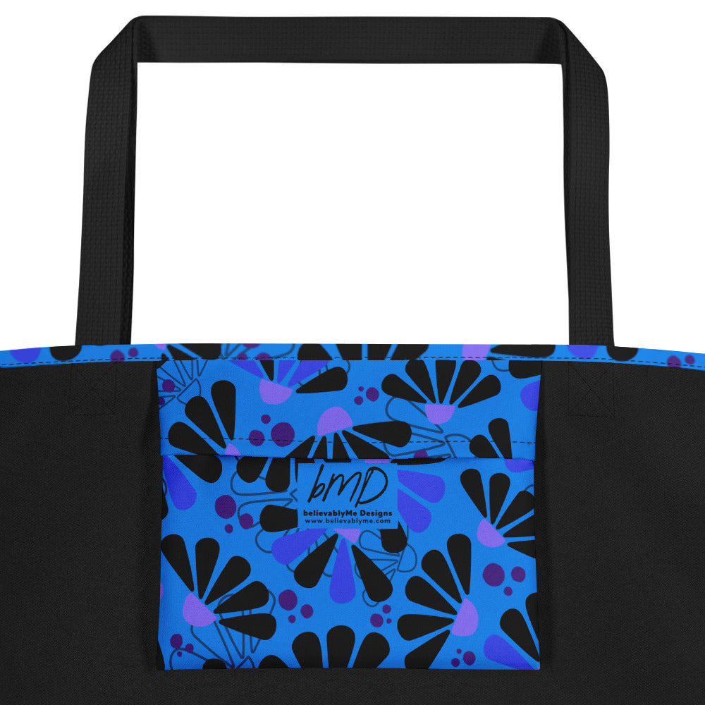 Blue tote bag with black handles, featuring a bold coneflowers pattern of black and purple abstract shapes resembling flowers; a vibrant and modern design.