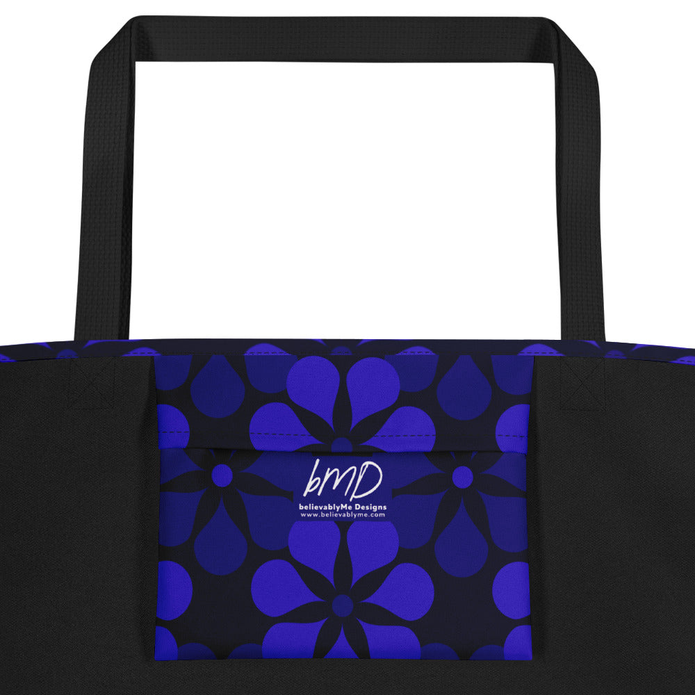 A tote bag with black handles features a vibrant, repeating pattern of abstract blue flowers on a dark background, creating a bold and modern look.