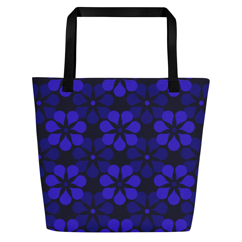 A tote bag with black handles features a vibrant, repeating pattern of abstract blue flowers on a dark background, creating a bold and modern look.