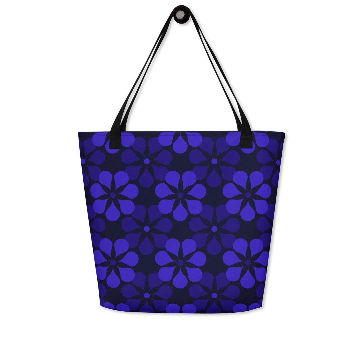 A tote bag with black handles features a vibrant, repeating pattern of abstract blue flowers on a dark background, creating a bold and modern look.