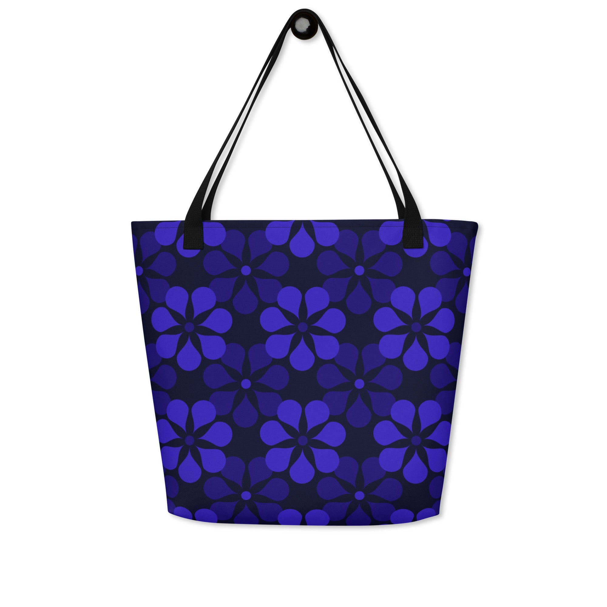A tote bag with black handles features a vibrant, repeating pattern of abstract blue flowers on a dark background, creating a bold and modern look.