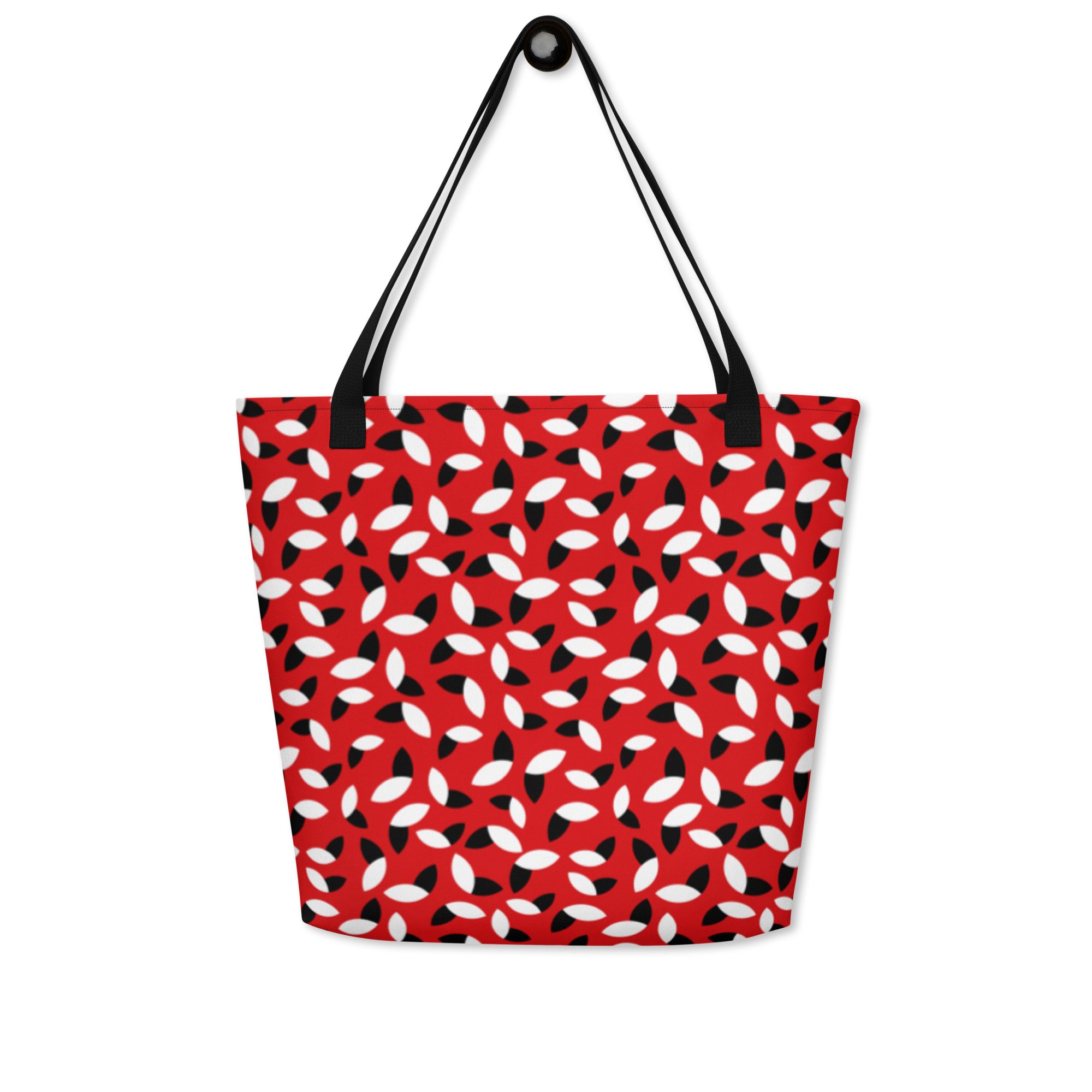 Red tote bag with a bold pattern of alternating black and white petal shapes. Features sturdy black handles, creating a modern and vibrant look.