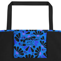 Blue tote bag with black handles, featuring a bold coneflowers pattern of black and purple abstract shapes resembling flowers; a vibrant and modern design.