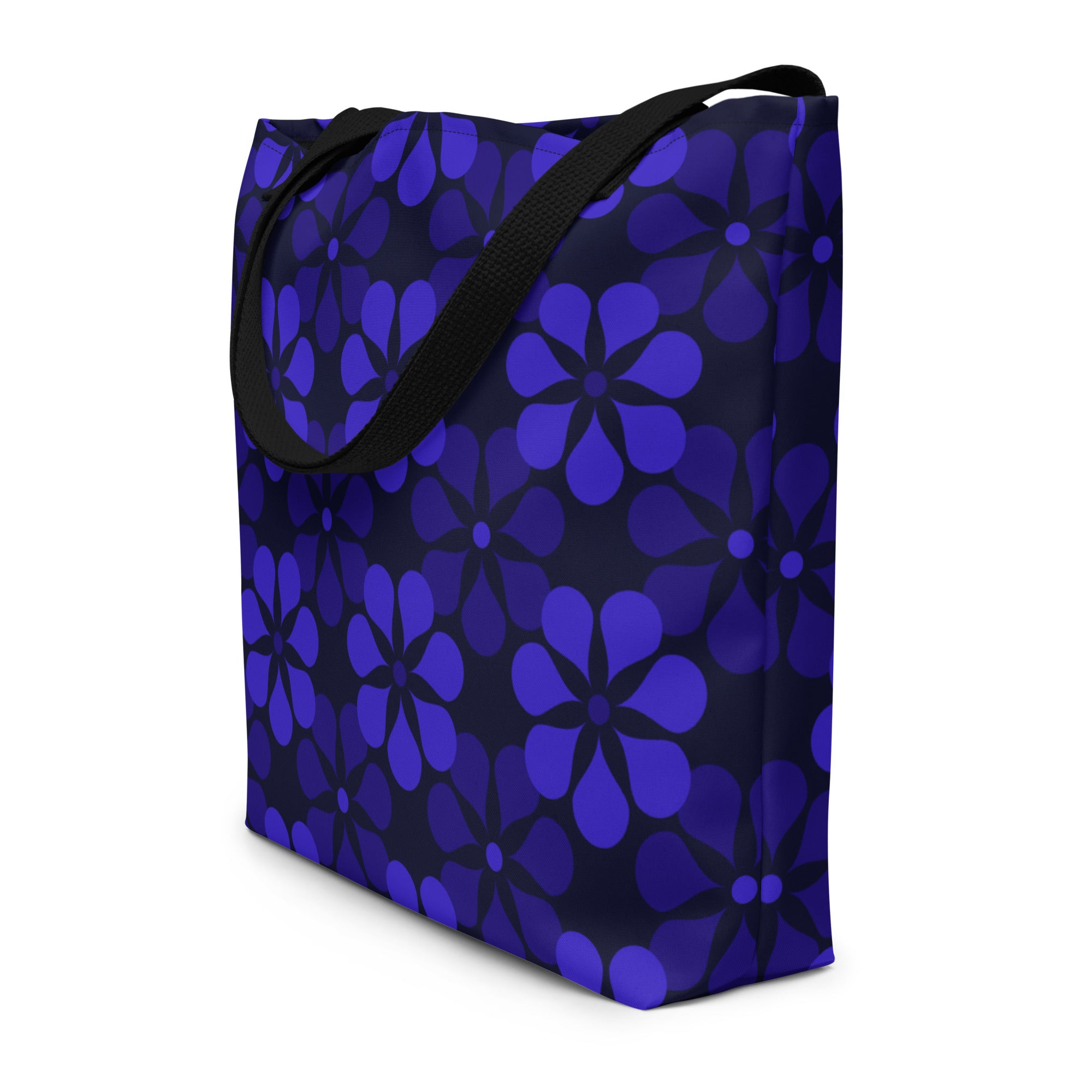 A tote bag with black handles features a vibrant, repeating pattern of abstract blue flowers on a dark background, creating a bold and modern look.