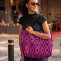  A woman in sunglasses smiles while carrying a vibrant tote bag featuring purple and pink diamond patterns. She's outdoors, creating a cheerful tone.